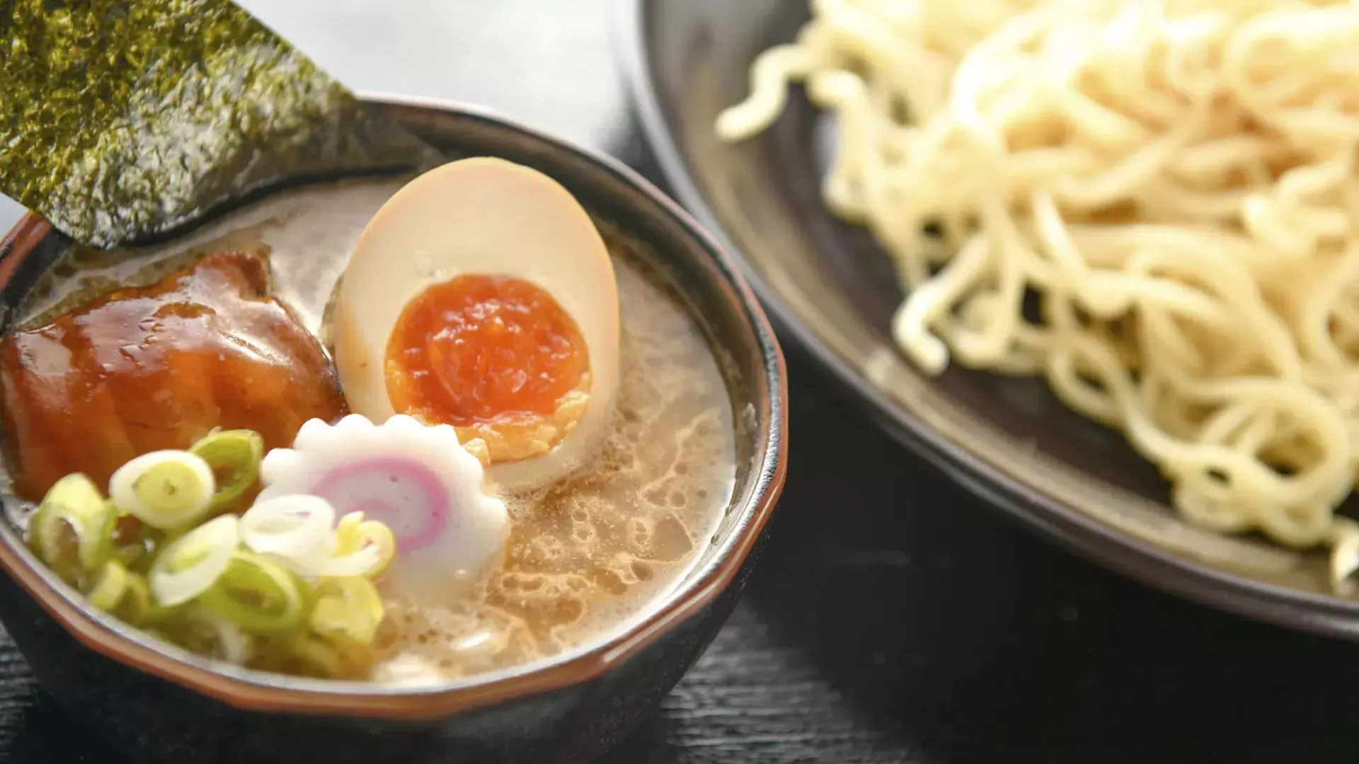 Primer plano de un plato de fideos y un plato de sopa de ramen con un huevo escalfado, 切.